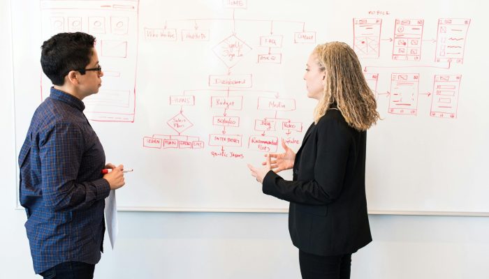 Two professionals brainstorming digital marketing ideas on a whiteboard.